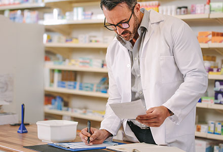 Apotheker unteschreibt Rezeot vor der Medikamenten Wand