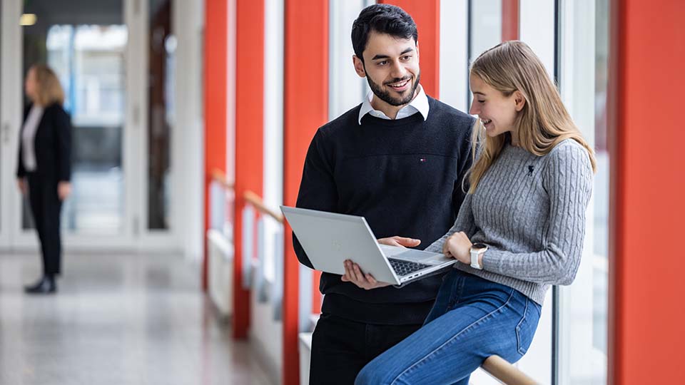 Eine Frau und ein Mann schauen auf ein Laptop