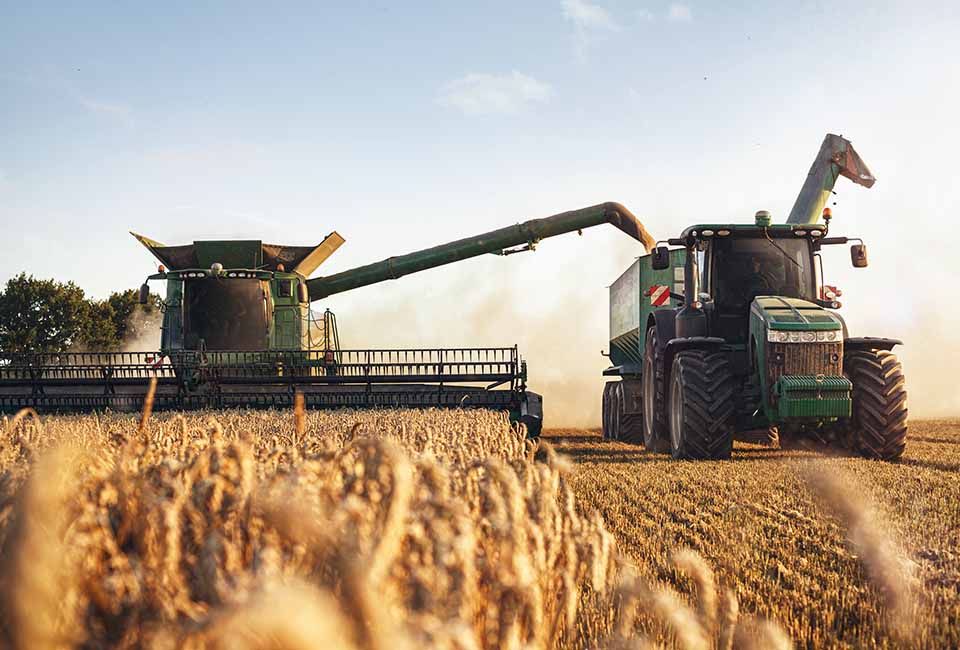 Ein Mähdrescher und ein Traktor fahren über ein Feld